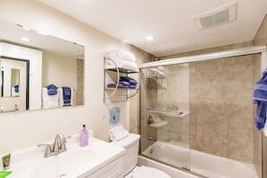 A modern bathroom with a glass-enclosed shower, a white sink with a mirror, and a towel rack with folded towels. - Private Resort Across street from beach (Siesta Key)