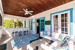 A covered outdoor area with a ceiling fan, white and blue furniture, and a patterned rug. - Private Resort Across street from beach (Siesta Key)