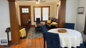 A dining area with a round table, blue chairs, and a ceiling fan.