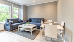 Un salon moderne avec un canapé gris, une table basse blanche et un coin repas comprenant une table et des chaises blanches.