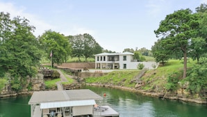 En fastighet vid en sjö med en brygga, ett hus och en liten båt.