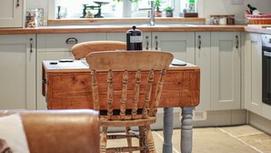 Une cuisine avec des meubles de rangement en bois, une table à manger et une chaise.