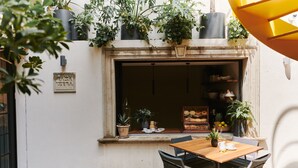 A patio area with a wooden table and chairs, surrounded by potted plants and a tiled floor. - Casa Izeba - Luxury Guest House (Mexico City)