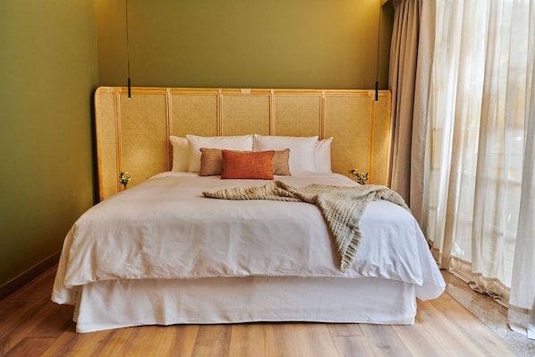A large bed with a woven headboard, a blanket, and pillows.