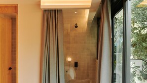 A modern hotel room with a bed, a chair, and a large window offering a view of greenery outside. - Casa Izeba - Luxury Guest House (Mexico City)