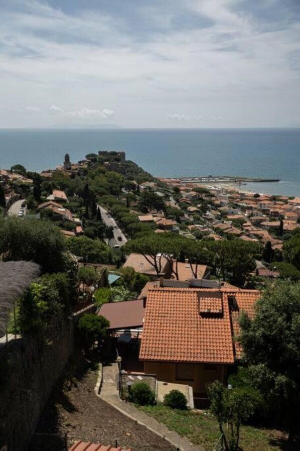 A coastal town with terracotta-roofed houses, a prominent tower, and a view of the sea.