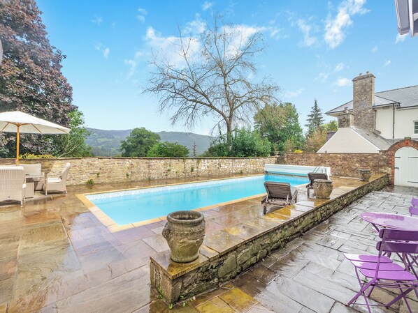 A swimming pool with lounge chairs and a stone wall.