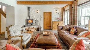 A cozy living room with a stone fireplace, leather furniture, and a wooden ceiling beam. - The Coach House - UK45027 (Crickhowell)