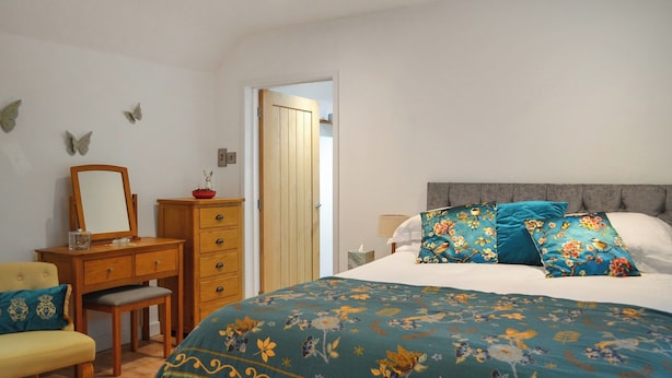 Een slaapkamer met een bed, een dressoir, een stoel en een spiegel.