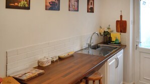 Een keuken met een houten aanrecht, witte kasten, een spoelbak en een raam met uitzicht.