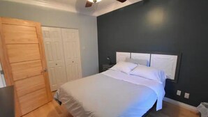 A bedroom with a bed, wooden door, and a ceiling fan.