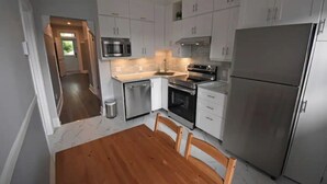 Een moderne keuken met witte kasten, roestvrijstalen apparatuur en een houten eettafel.