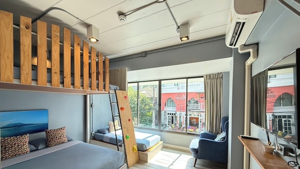 Quarto moderno com uma cama beliche, uma escrivaninha, uma cadeira e uma grande janela com vista para a cidade.