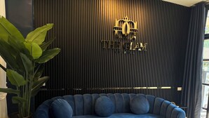 Uma sala de estar moderna com um sofá azul, uma mesa de centro preta e uma planta grande.