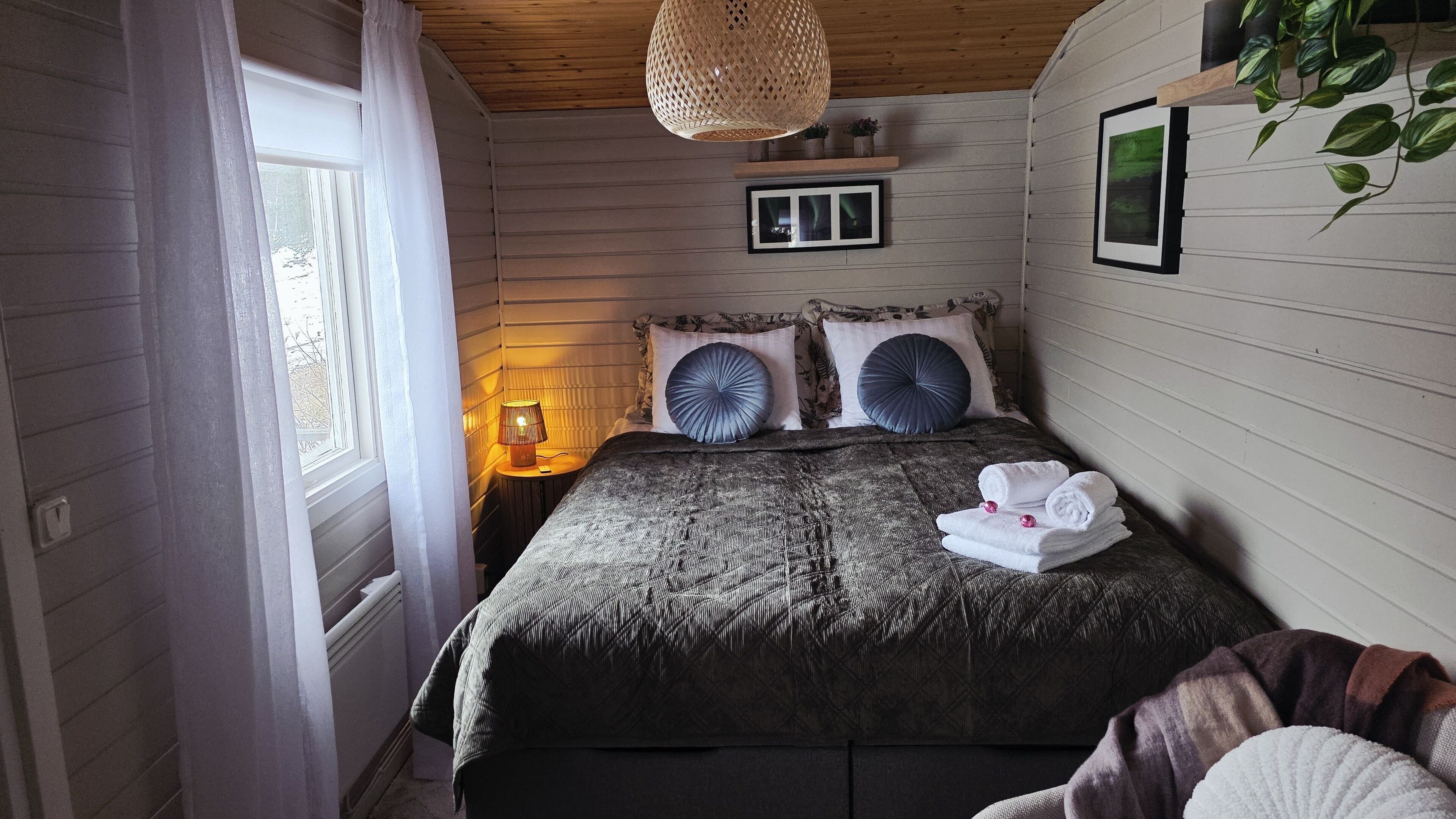 Un dormitorio acogedor con cama, lámpara de noche y ventana con cortinas.