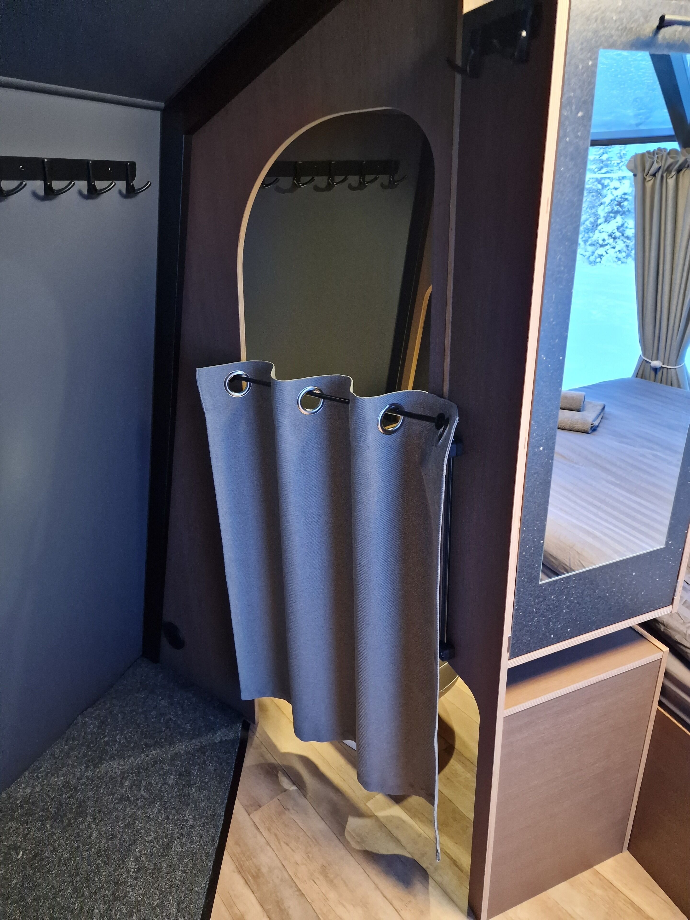 A bathroom with a shower curtain, a mirror, and a wooden floor.