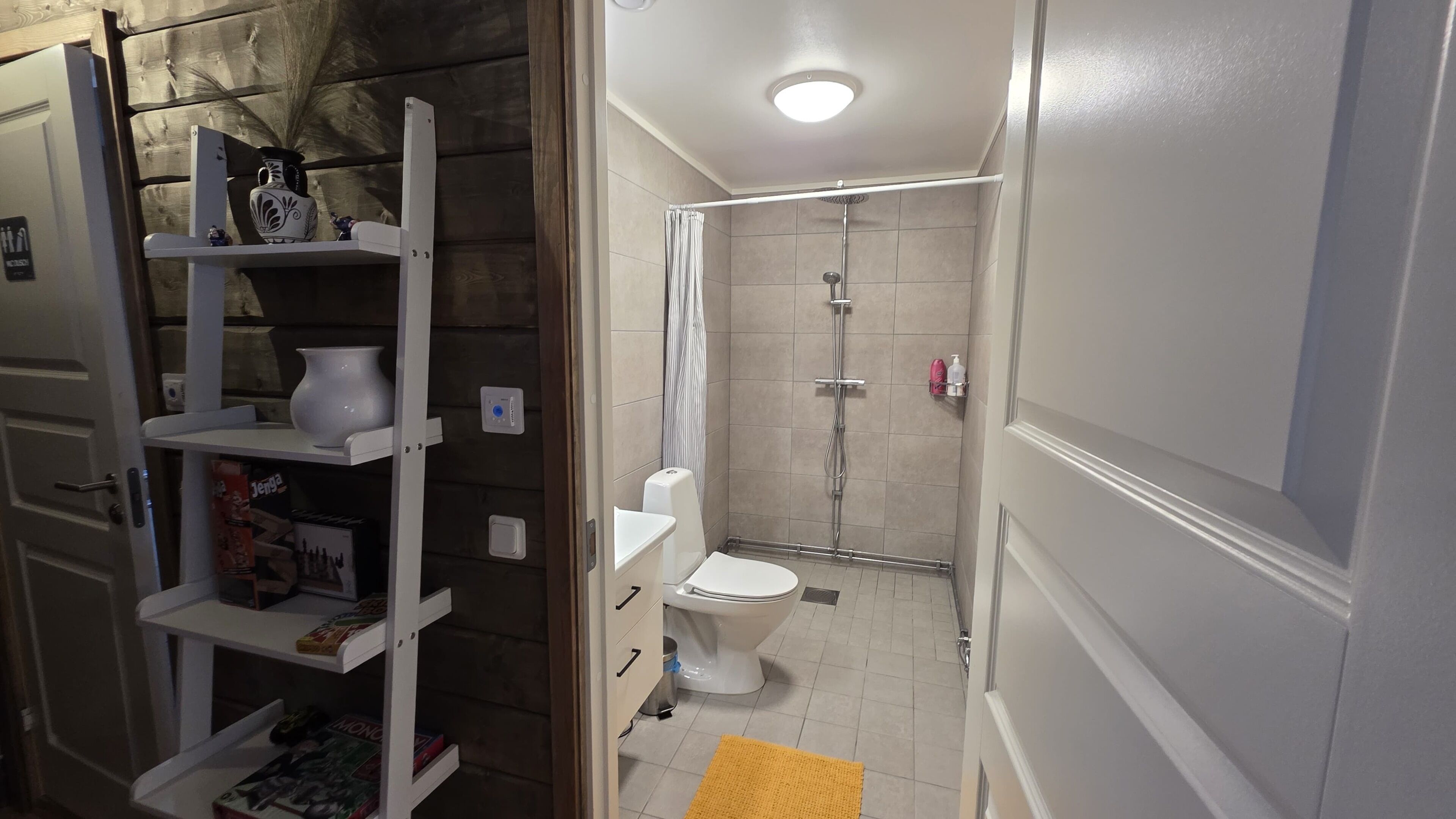 Ein kleines Badezimmer mit Toilette, Dusche und Ablagen für Toilettenartikel.