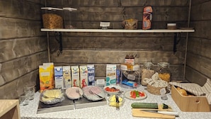Una kitchenette con diversos alimentos y condimentos, entre ellos lácteos, pan y verduras.