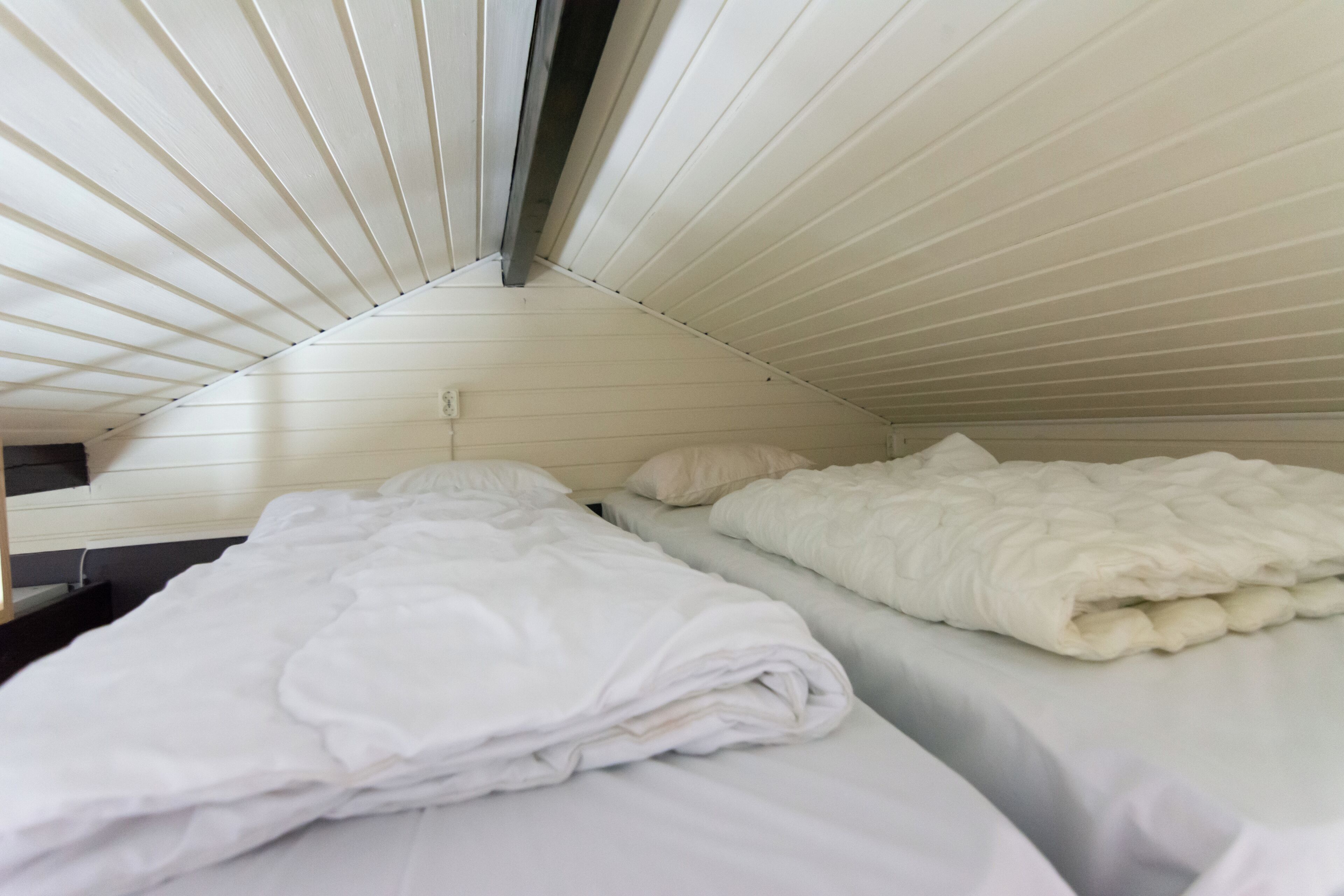 A room with two beds, each with white bedding and a headboard.