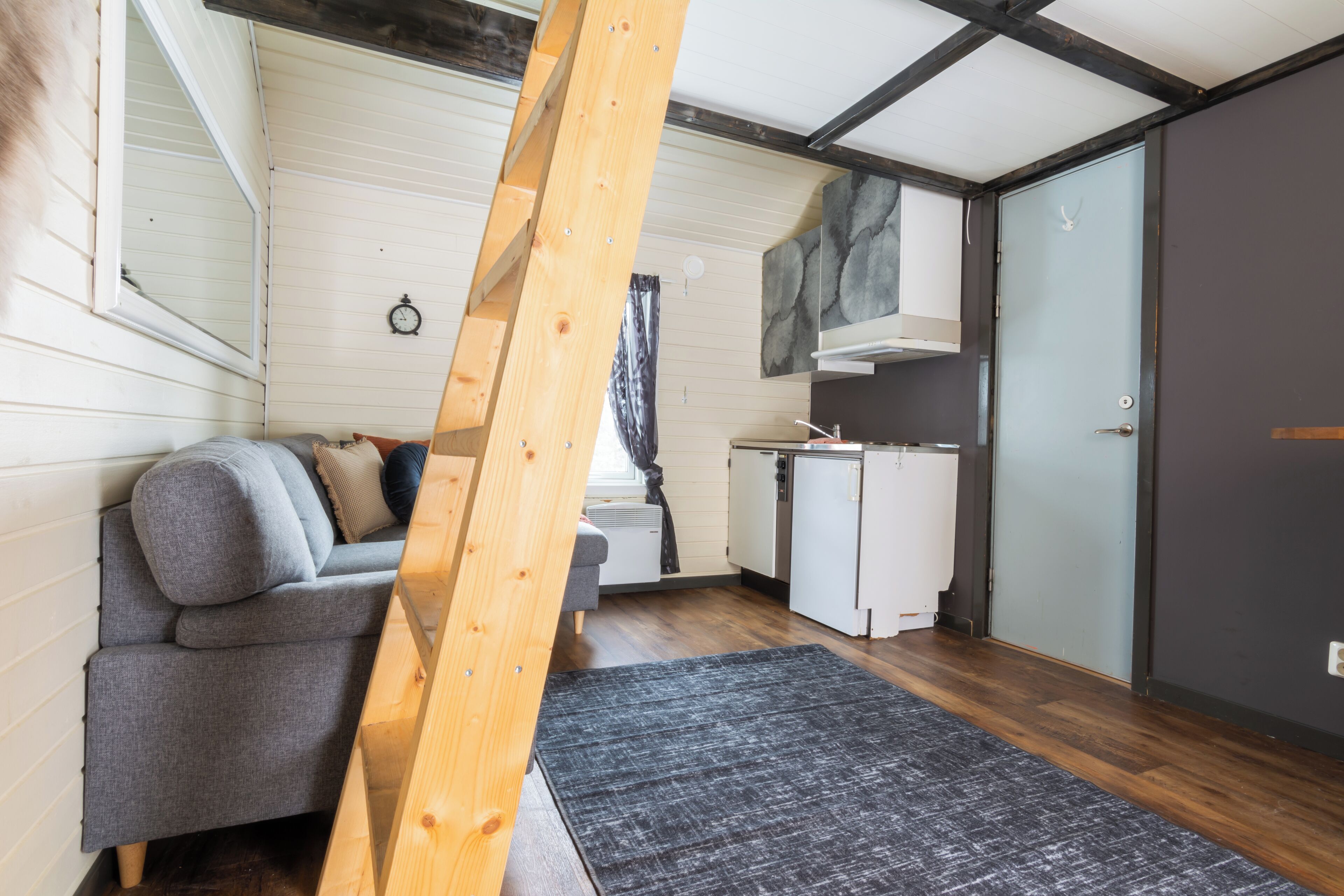 Un espacio habitable pequeño con sofá, kitchenette y puerta corredera.