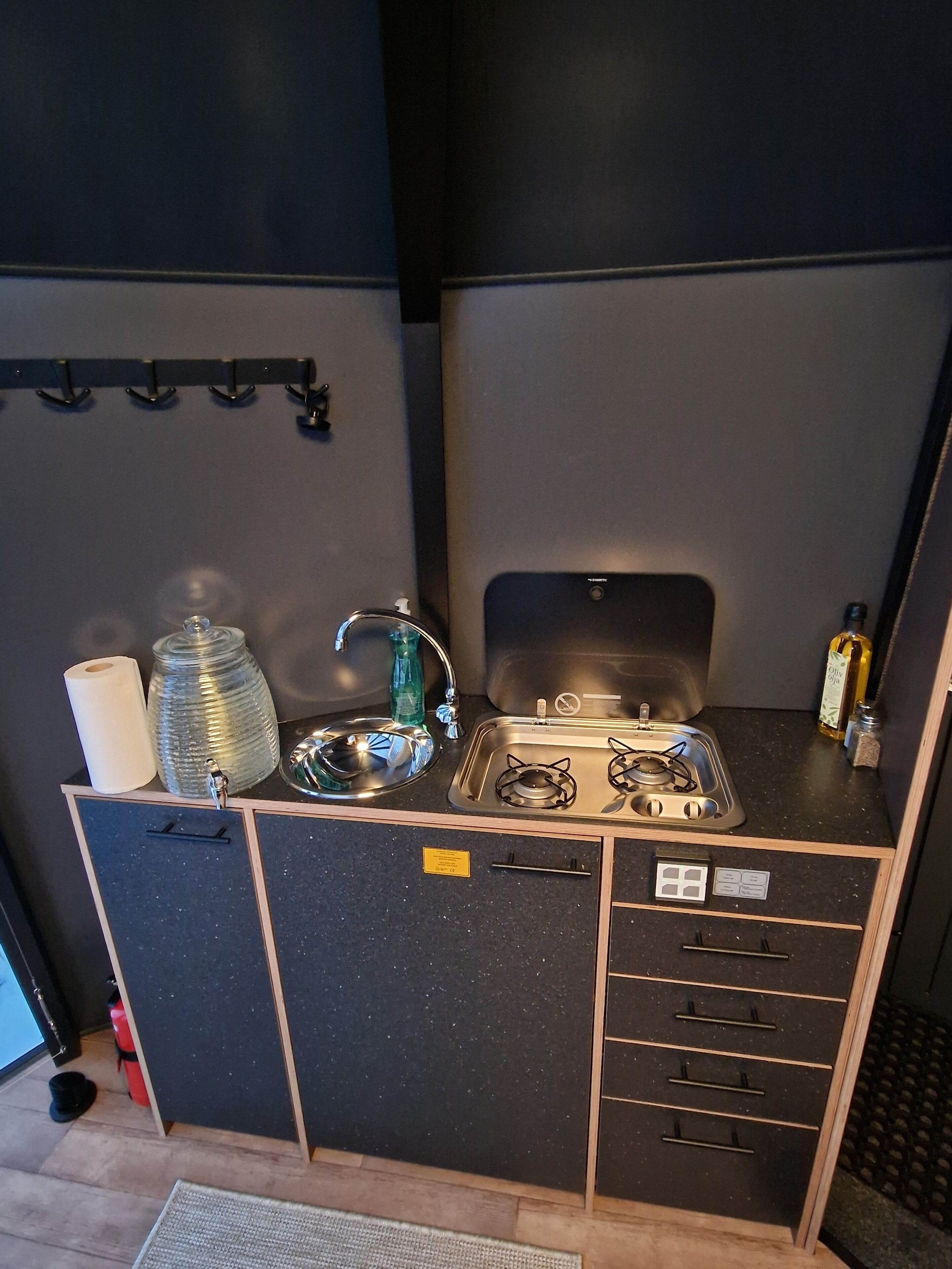A compact kitchenette with a gas stove, sink, and storage drawers.