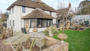 A white house with a thatched roof, a garden with a seating area, and a greenhouse. - 2 bedroom accommodation in Reedham (Reedham)
