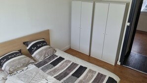Un dormitorio con una cama, dos almohadas, un cabecero, un armario y una puerta.