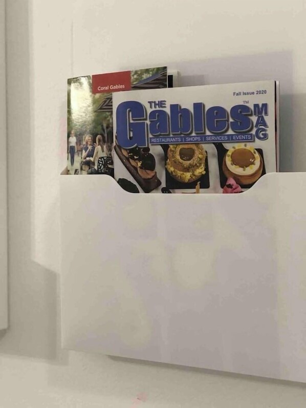 A magazine rack with 'The Gables' magazine, featuring a cover with food images. - Cozy Studio Apartment (Miami)