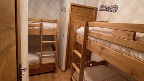 Habitación con literas de madera, una lámpara en el techo y una puerta.