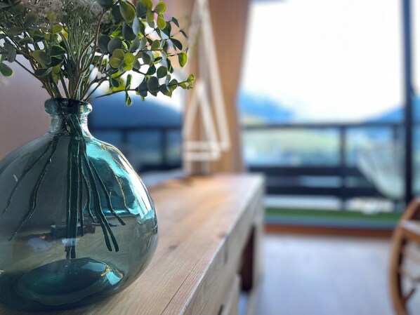 A clear view of a room with a wooden table and a glass vase with green foliage. - The White Bear - Spacious and Comfortable Apartment (La Clusaz)
