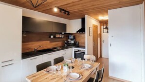 Una cocina moderna con armarios de madera, una encimera negra y una zona de comedor preparada para cuatro comensales.