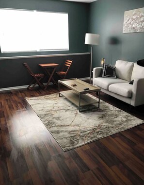 A living room with a dark green wall, a white sofa, a wooden coffee table, and two wooden chairs. - Renovated Apartment In Ottawa (Ottawa)