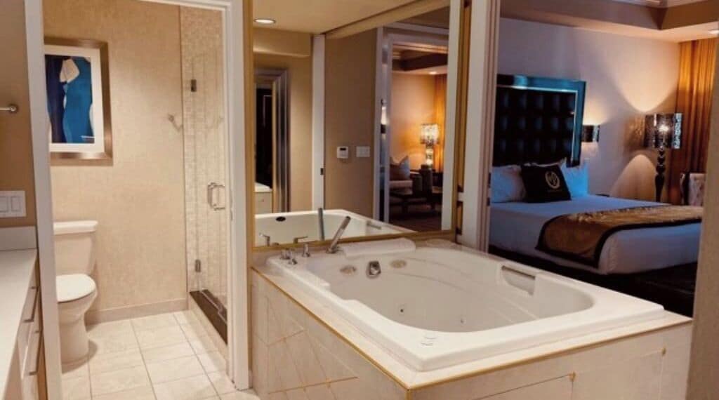 A modern hotel bathroom with a large bathtub, a toilet, and a mirror.