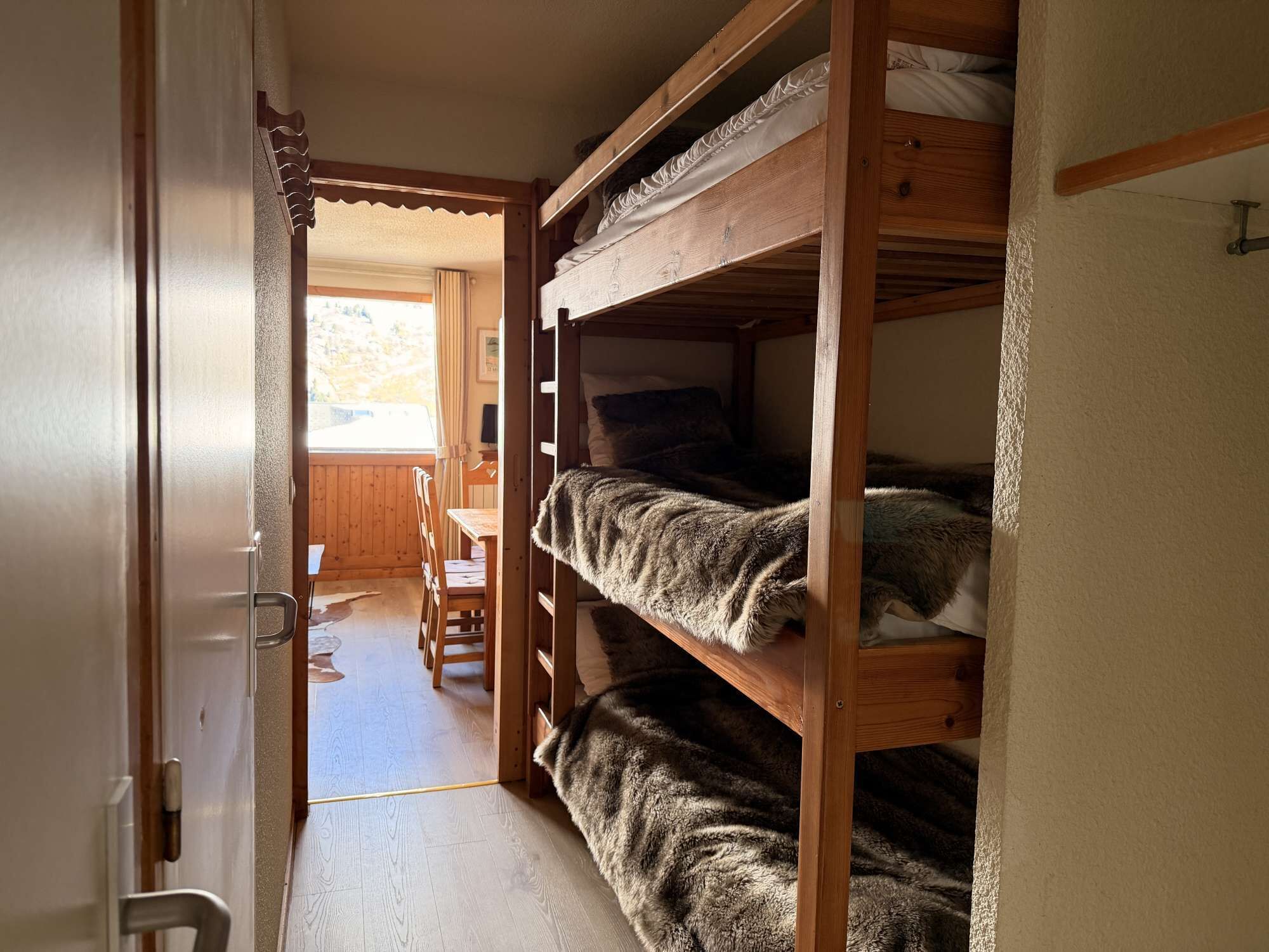 A bunk bed room with a wooden door and a view of a dining area.
