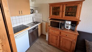 A compact kitchen with a dishwasher, a microwave, and a coffee maker. - Apartment of 30m2 with 1 room, 1 bunk bed area and 1 living room with sofa (Les Allues)