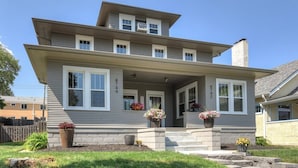 A two-story house with a front porch, a chimney, and a well-maintained lawn. - Capitol Charm in Dundee - East (Omaha)