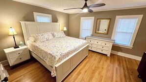 A bedroom with a bed, nightstands, dresser, and a ceiling fan. - Capitol Charm in Dundee - East (Omaha)