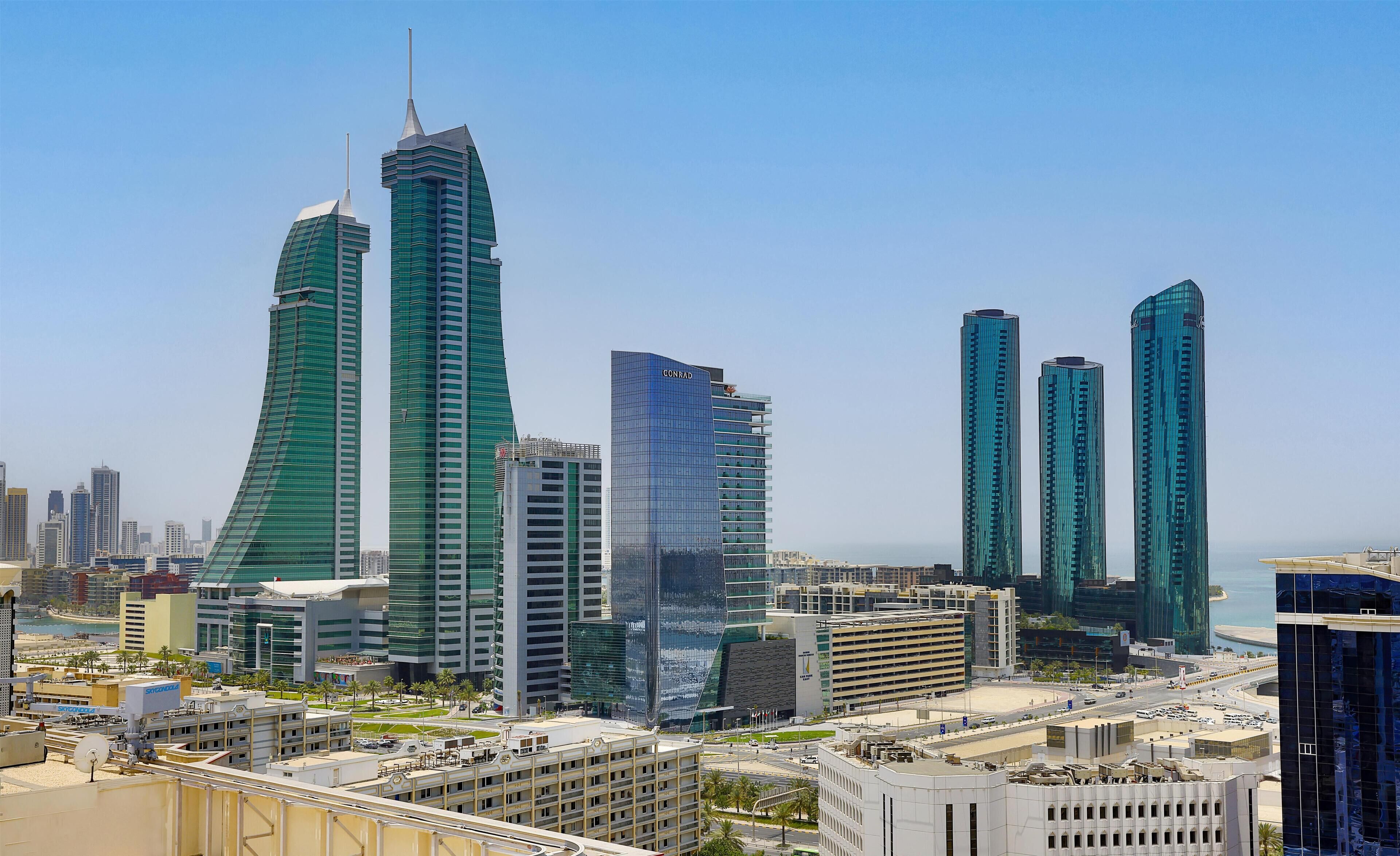 A cityscape with modern high-rise buildings, including a prominent curved skyscraper and several rectangular glass towers.