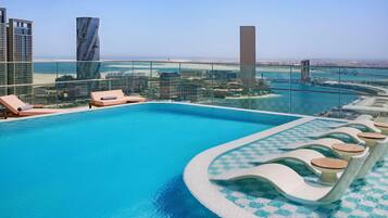 Una piscina al aire libre, sillones reclinables de piscina