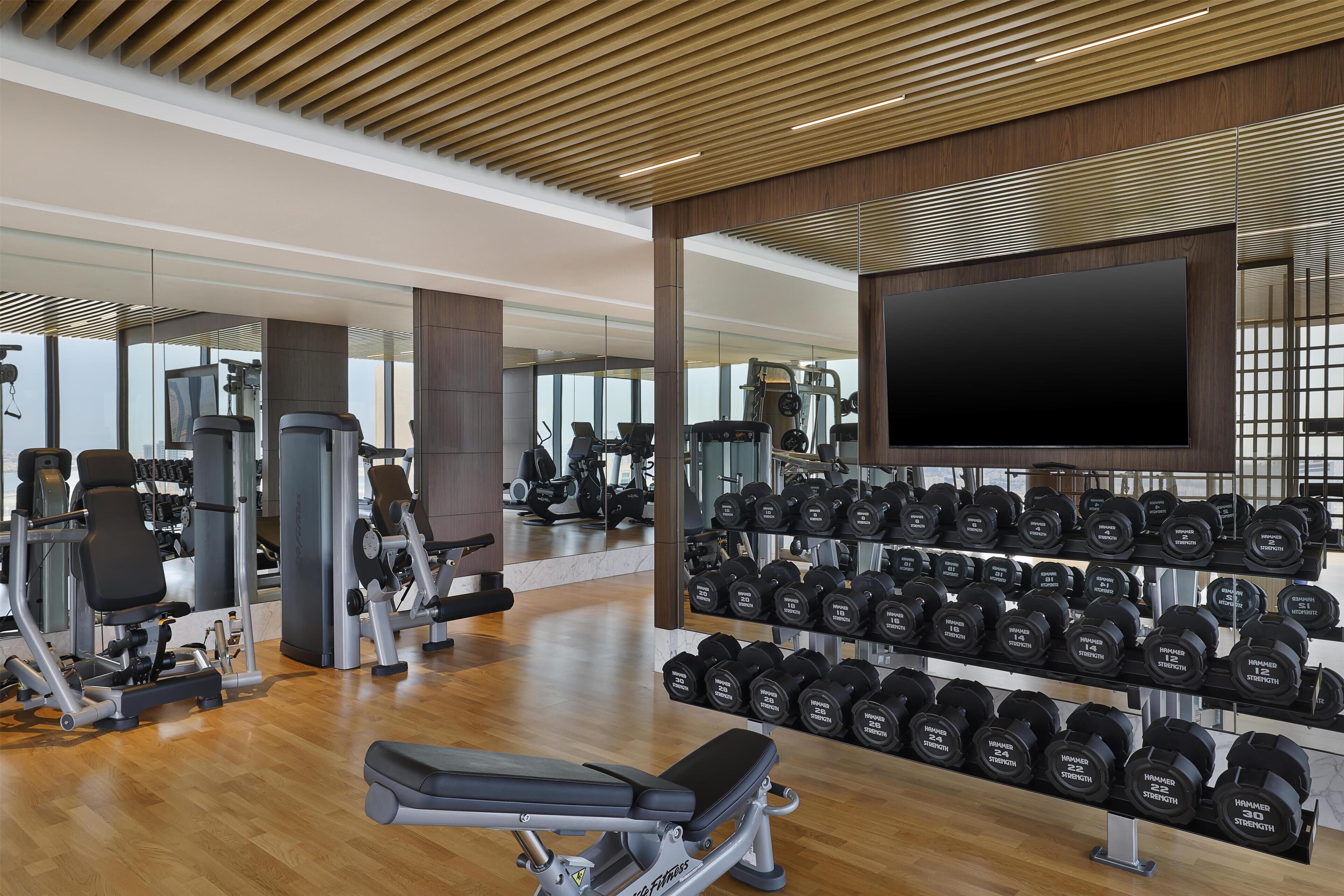 Una sala de gimnàstica amb equip d'exercici, una banca i una paret de peses.