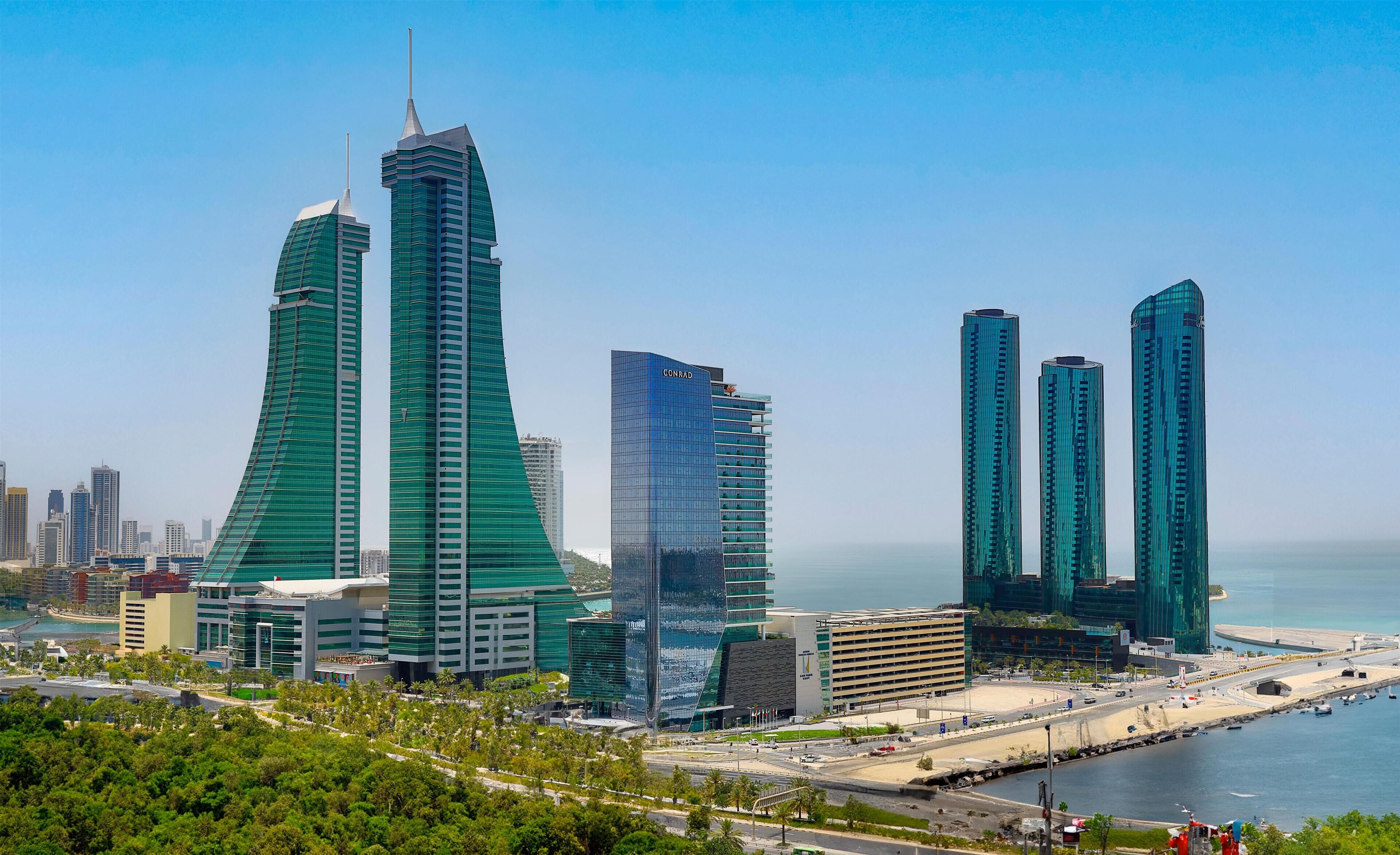 A cityscape with modern skyscrapers, including a prominent building with a unique curved design and another with a sharp, angular structure.