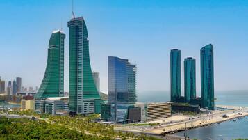 A cityscape with modern skyscrapers, including a prominent building with a unique curved design and another with a sharp, angular structure.