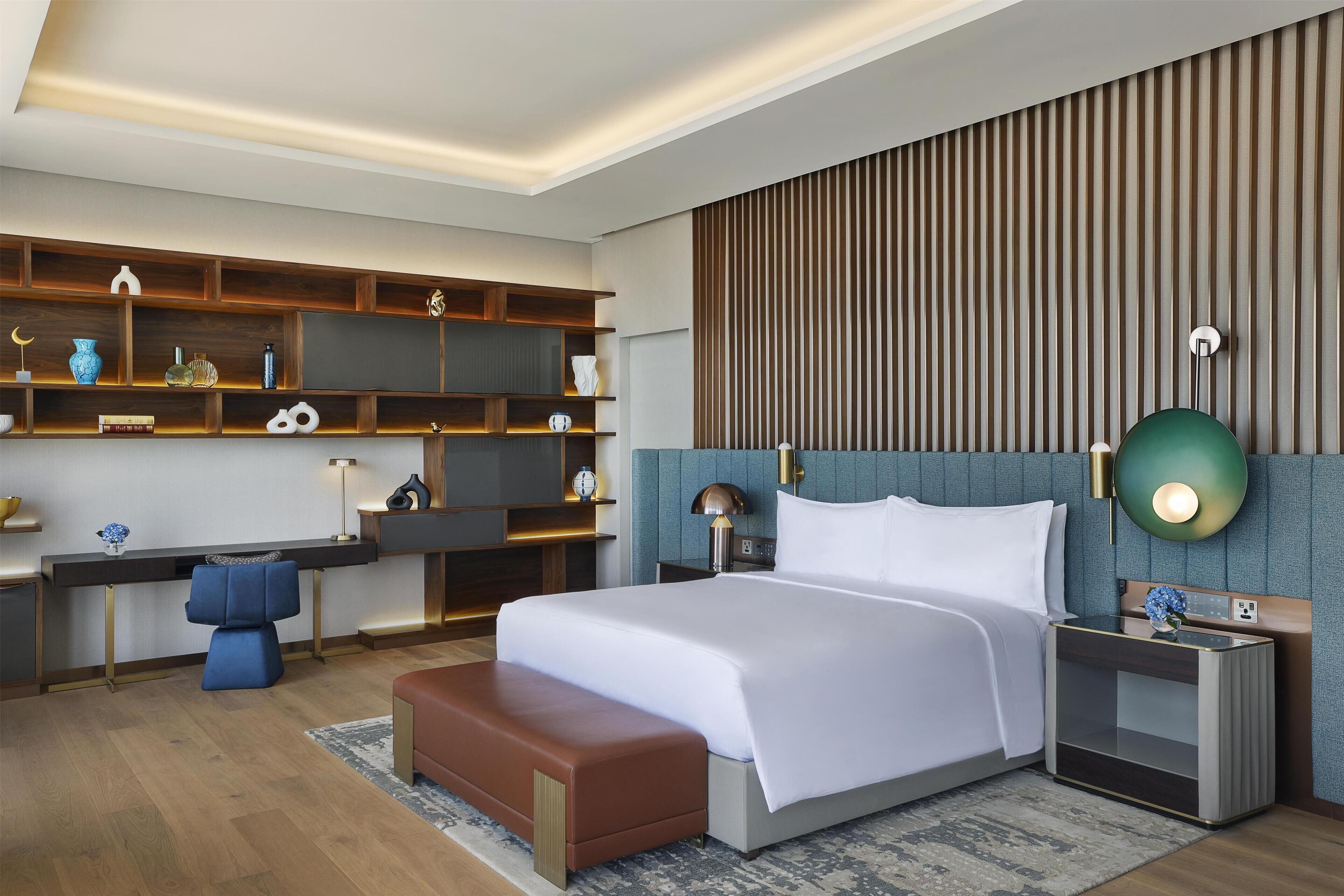 A modern hotel room with a large bed, a desk, and a seating area.
