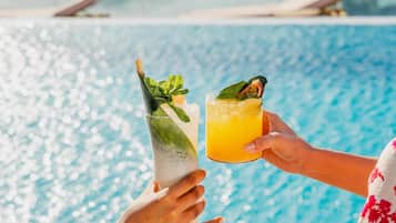 Two people holding drinks by a poolside.