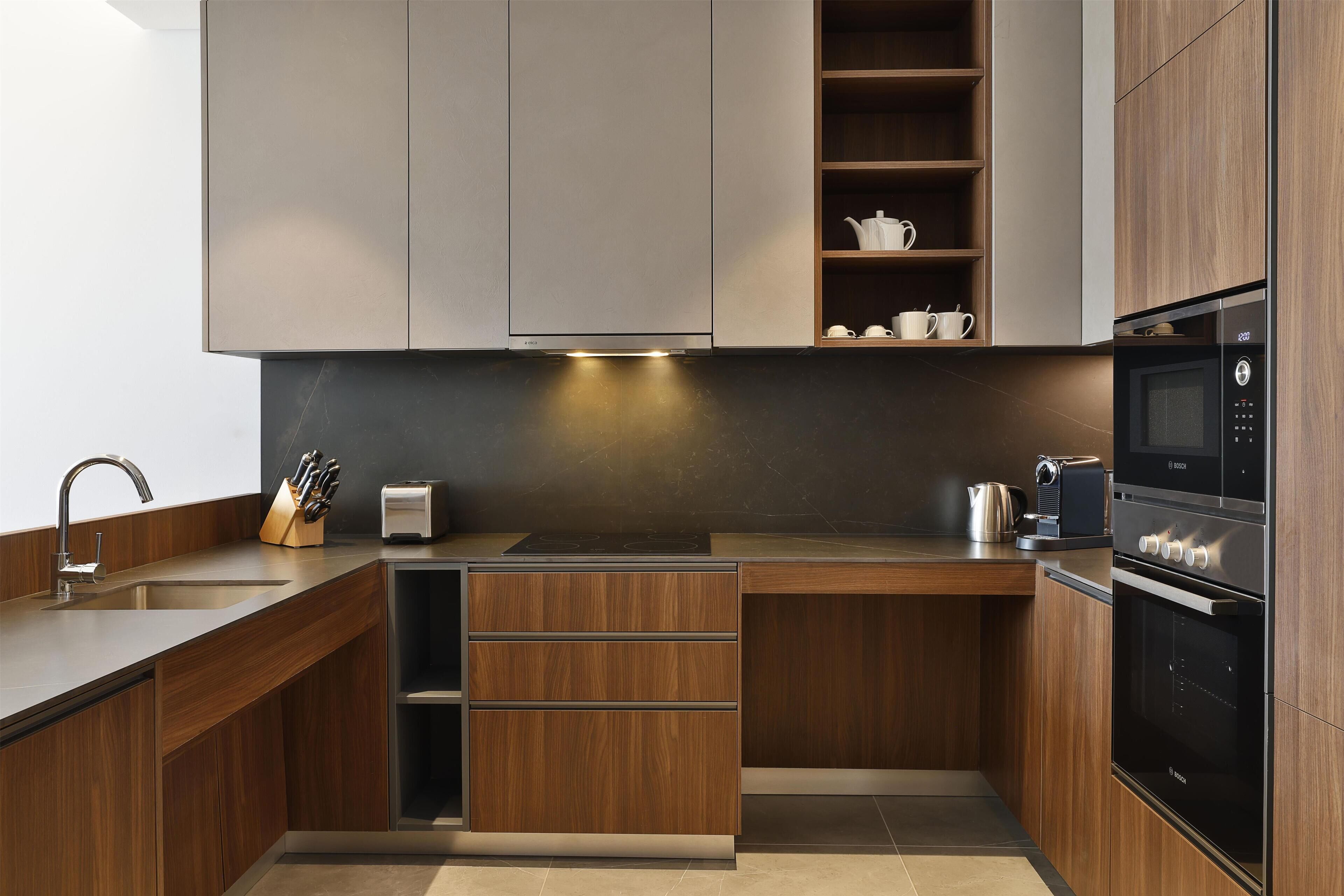 A modern kitchen with wooden cabinets, a built-in oven, and a coffee maker.
