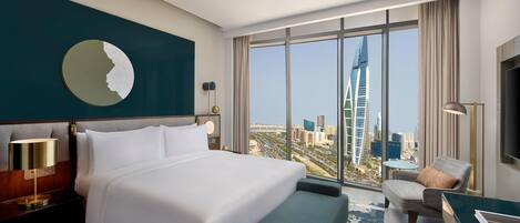 A hotel room with a large bed, a desk, a chair, and a view of a cityscape.