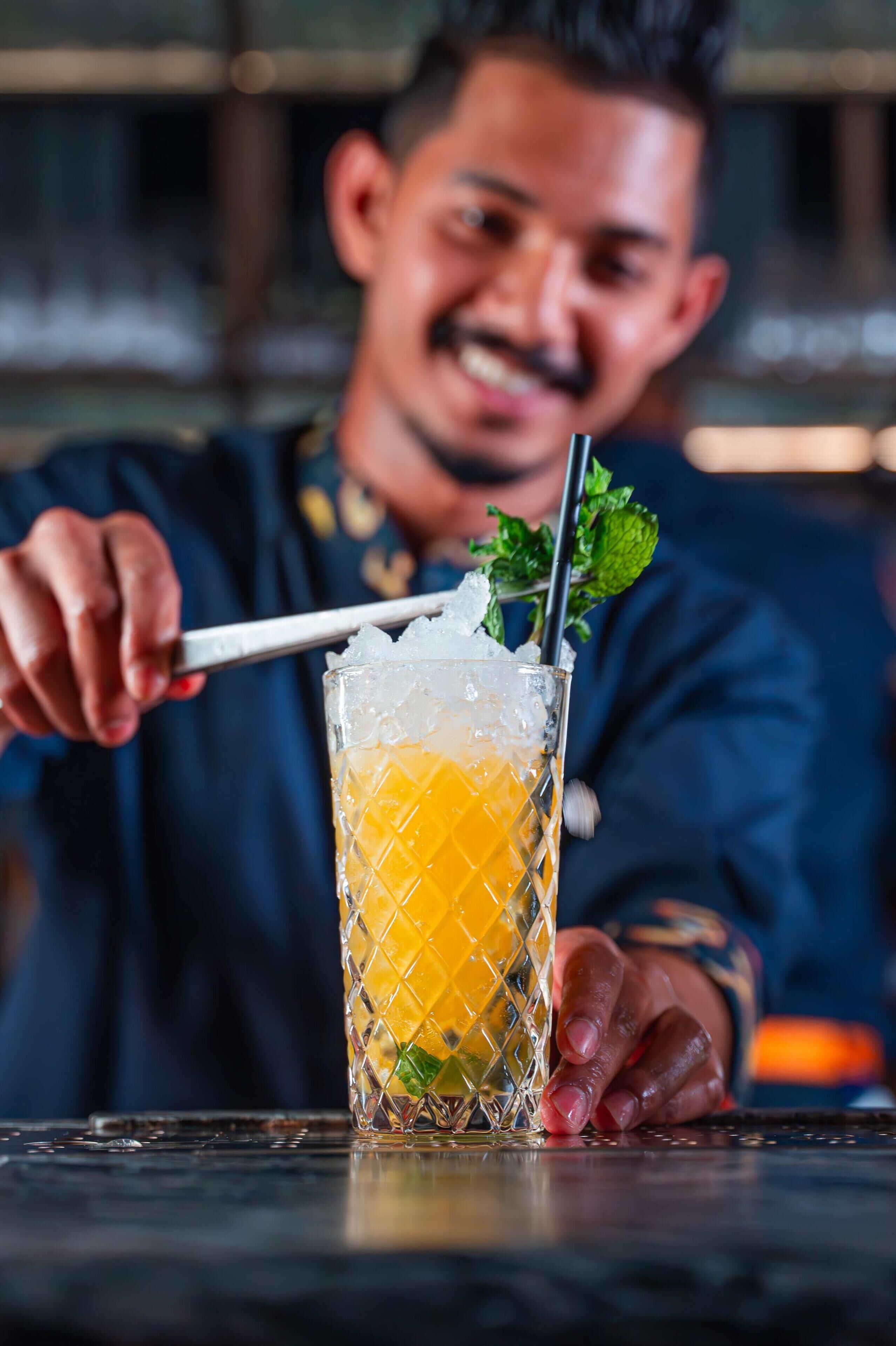 Une personne tenant un verre à cocktail contenant des glaçons et une paille.