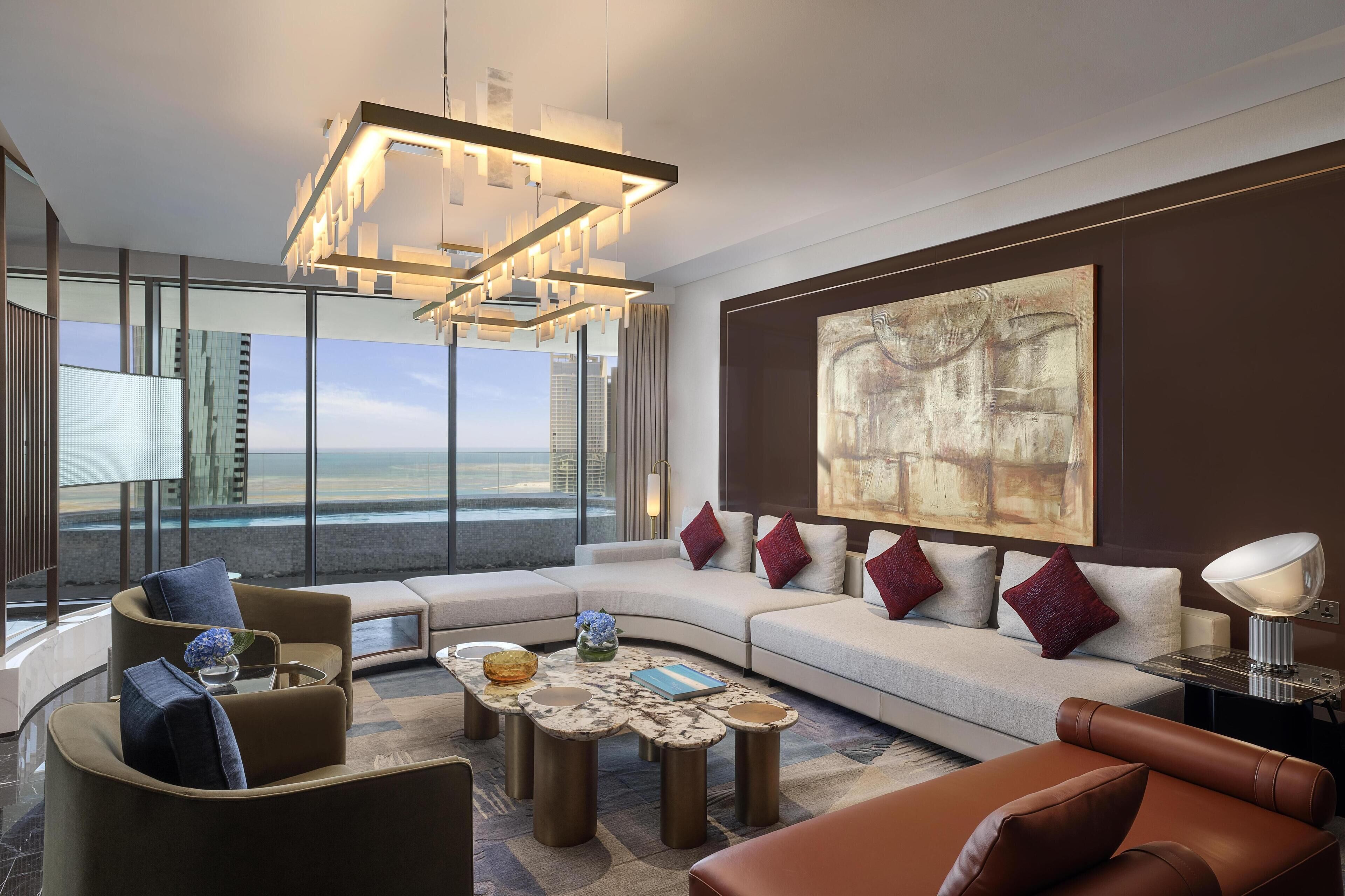 A modern living room with a curved sofa, a coffee table, and a large abstract painting on the wall.