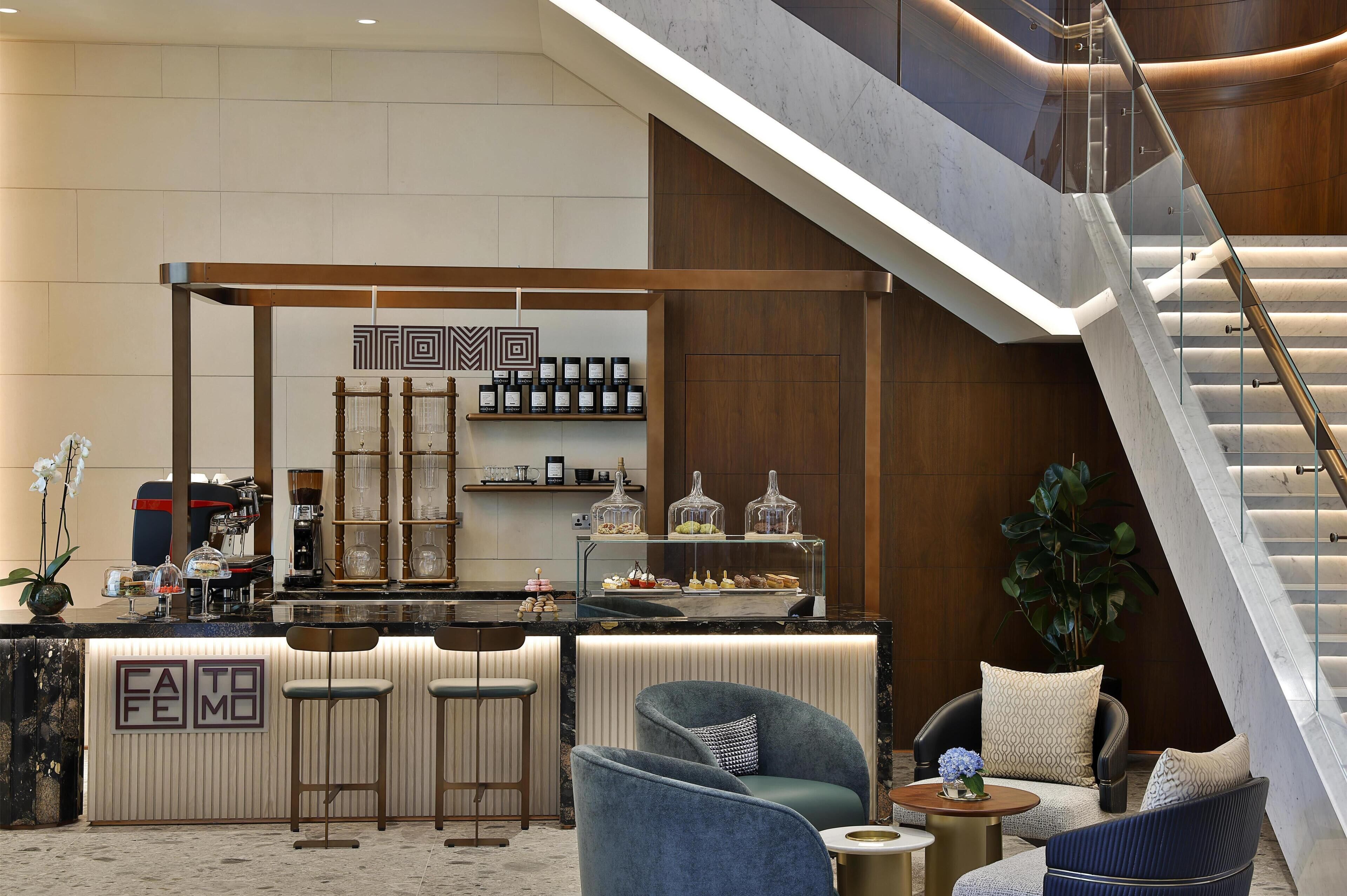 Een moderne hotellobby met een bar, zitgedeelte en een trap.
