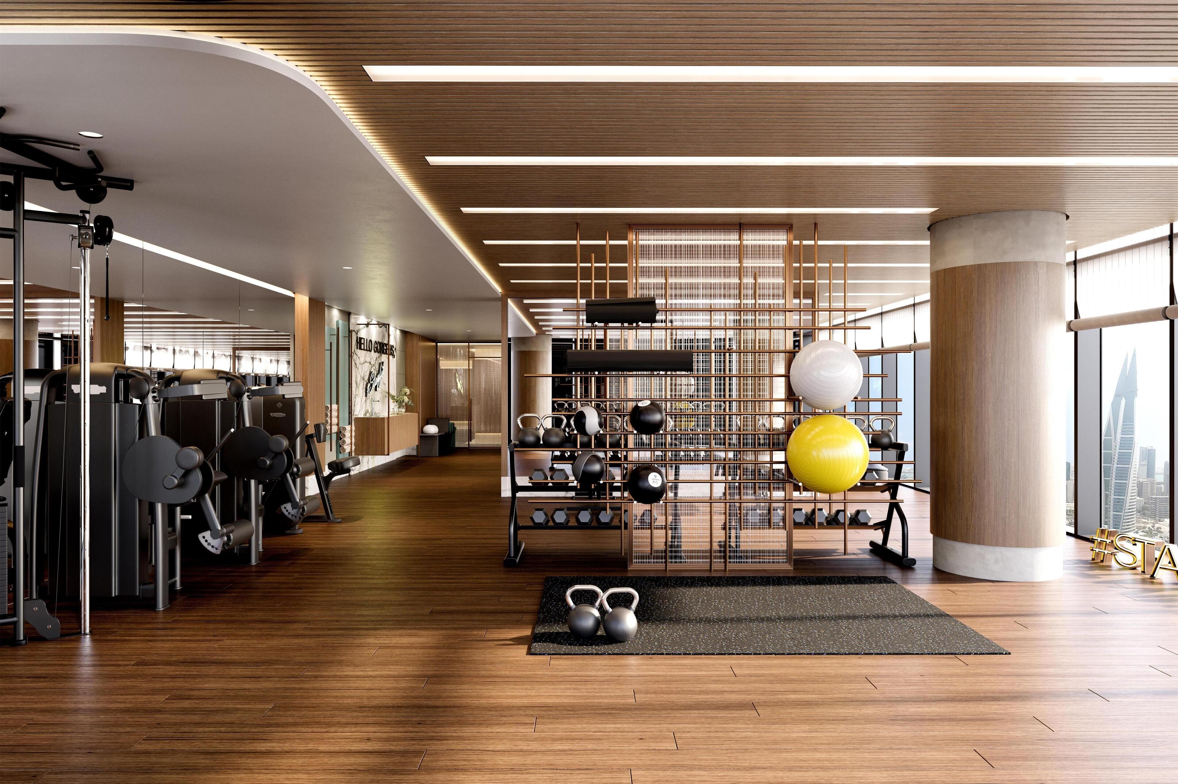 A modern gym with various exercise equipment, a kettlebell set, and a large window offering a city view.